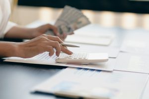 Female hands using a calculator and counting money.